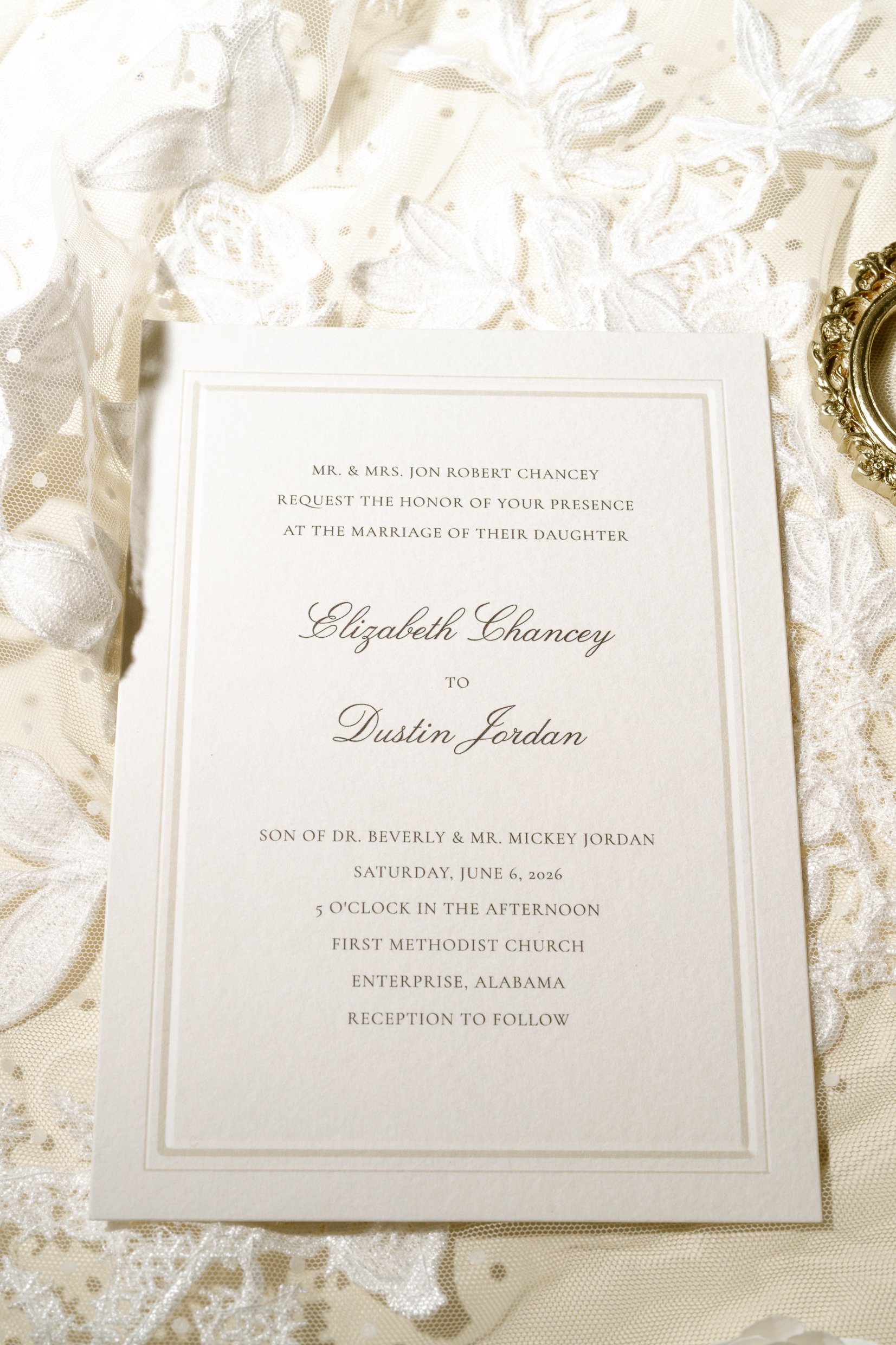 The invitation to Elizabeth Chancey and Dustin Jordan's wedding resting on a bed of lace.