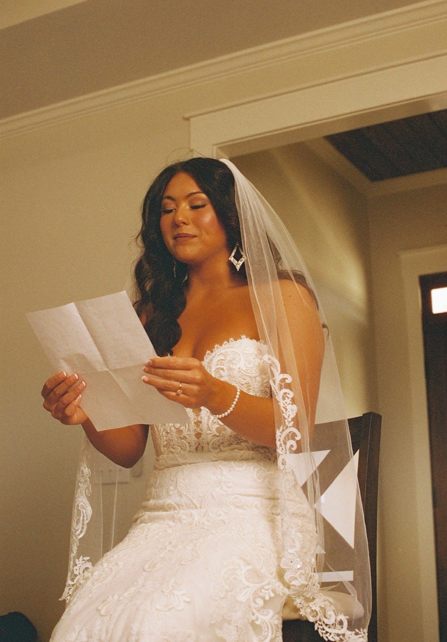 Raley reading a handwritten letter in her wedding dress and veil at Dalrymple Farms, photographed on film.