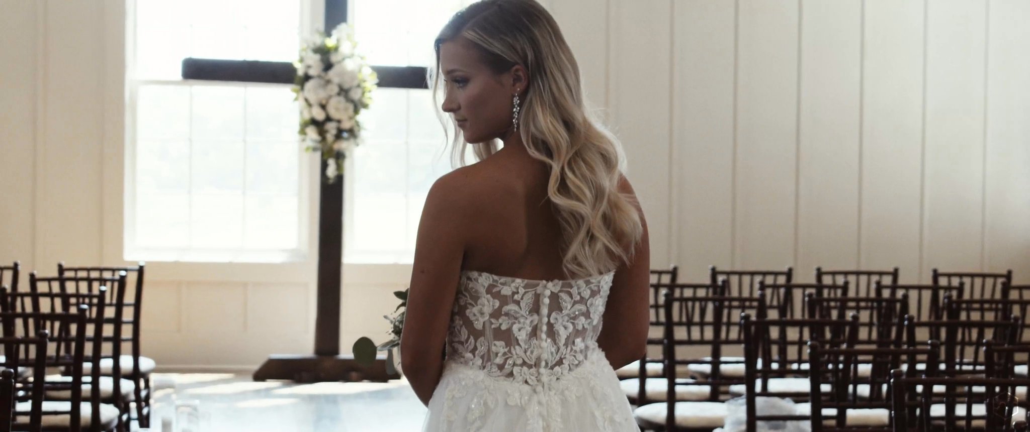 Madalyn looks back in her wedding dress before her first look with Caleb. Still from their Midsummer Productions wedding film.