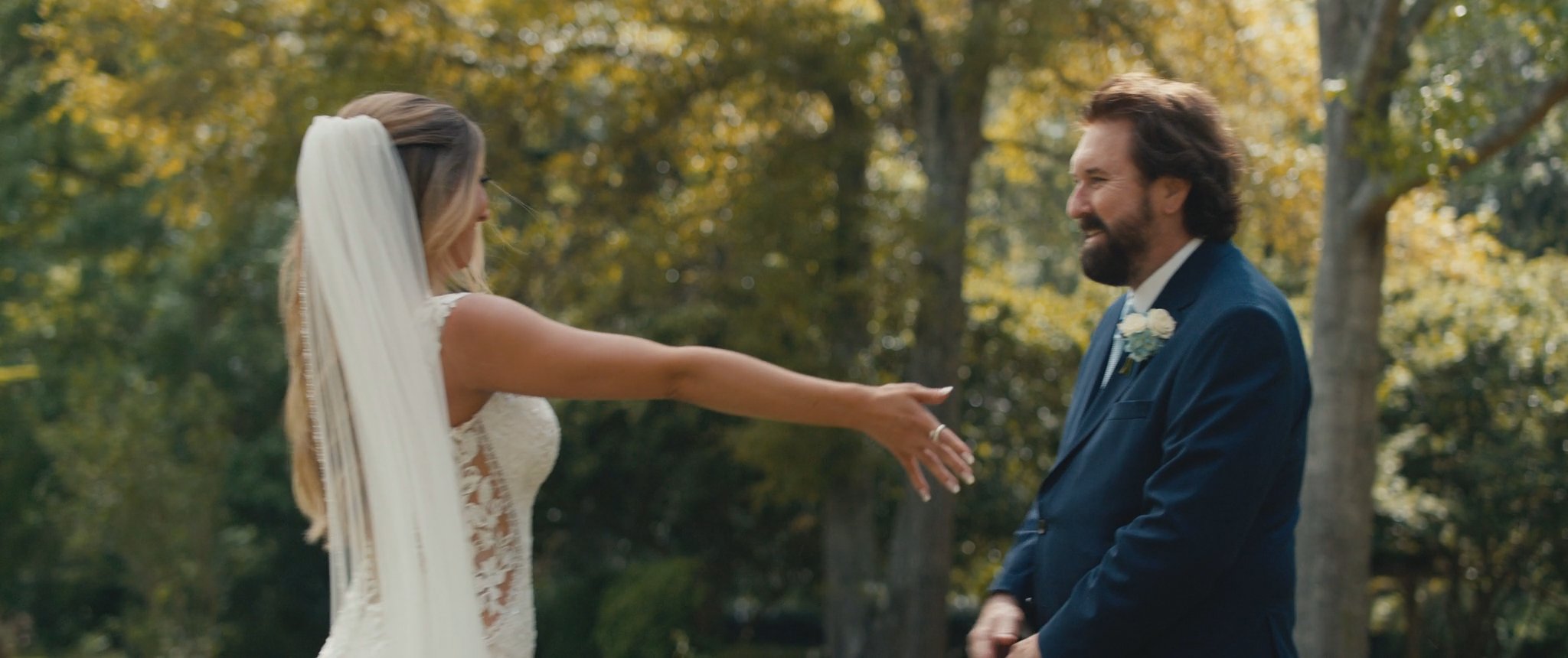 Montana and her dad reaching toward each other at their first look. Still from their Midsummer Productions wedding film.