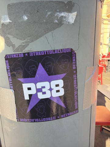 A rectangular graphic sticker is prominently displayed on a weathered metal utility pole. The sticker features bold text and a star motif, reinforced by silver duct tape on its sides.. Subject: The text 'P38' superimposed on a purple star with repeating line-art portraits in the background.. Style: Graphic vector illustration with a focus on bold typography.. Details: The sticker includes social media handles around the border and features stylized line-drawn faces of a man with an afro and glasses.. Shape: rectangular. Setting: Urban outdoor environment. Surface: A cylindrical metallic utility pole or street light post.. Colors: #8A2BE2 (Violet Star), #FFFFFF (White Typography), #000000 (Black Background), #808080 (Grey Metal Pole). Composition: Close-up, centered on the sticker with a shallow depth of field that blurs the street scene behind.. The sticker appears to be promotional material for a musical collective or underground culture movement. By utilizing a five-pointed star and bold alphanumeric codes, it adopts a visual language of political rebellion or 'vanguard' status, re-contextualizing these symbols for modern urban self-promotion.
