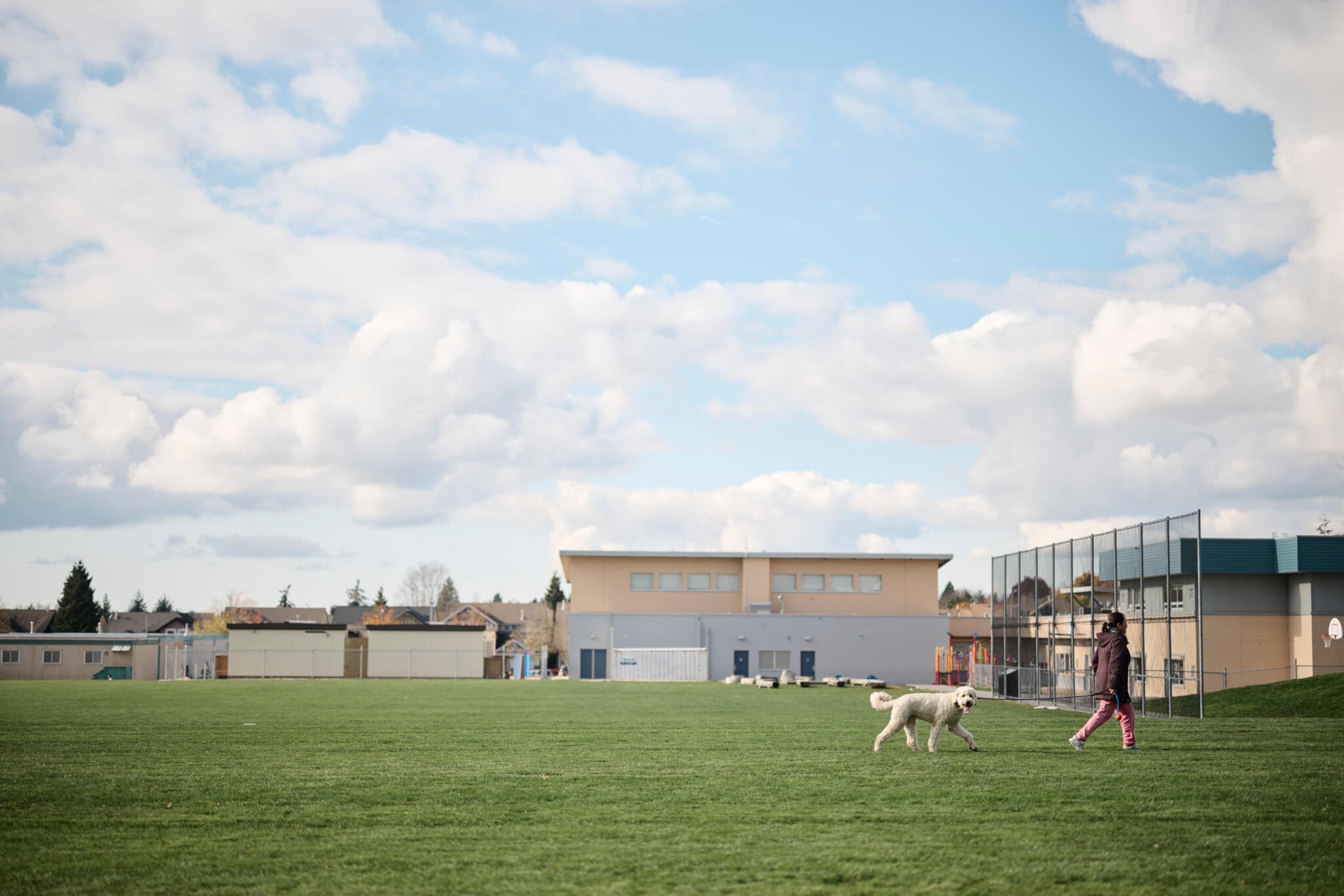 http://Woman%20walking%20a%20dog%20through%20a%20school%20field