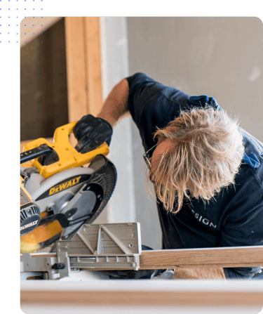 Construction worker using a yellow miter saw to cut a wooden board during his rotational shift
