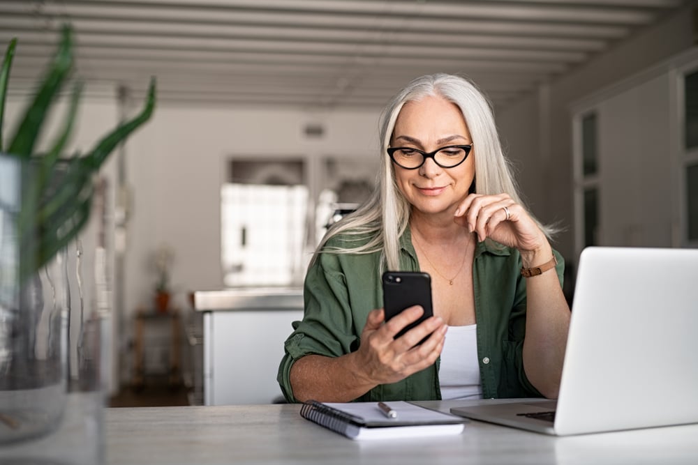 white-hair-woman-green-shirt-on-phone-and-laptop-1.jpg
