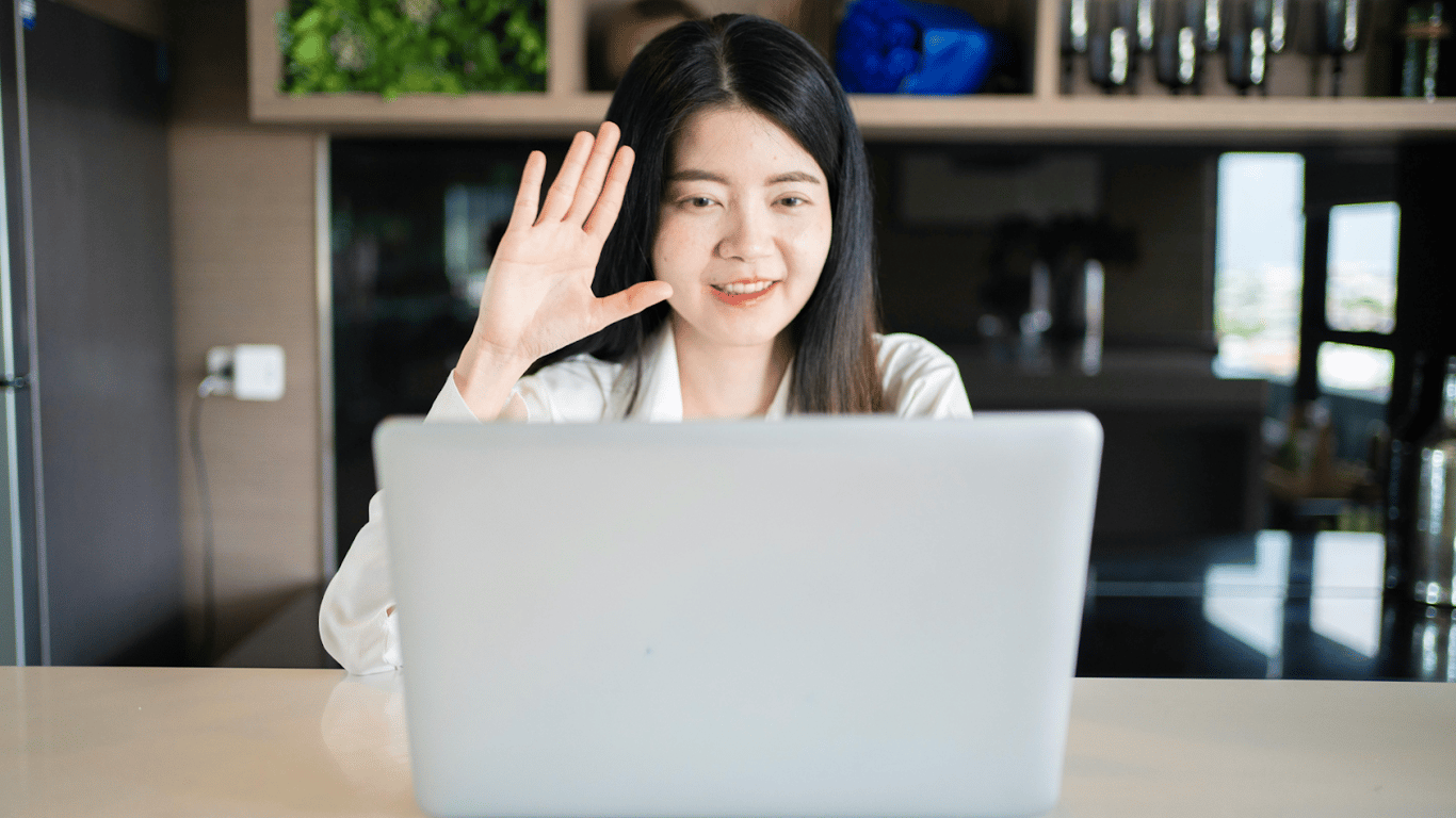 Woman waving on video call.png
