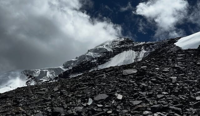 Rocky mountain slope with snow and dramatic clouds