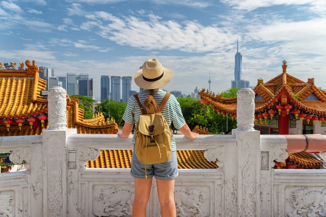 Traveler overlooking city skyline with pagoda rooftop, Malaysia holiday