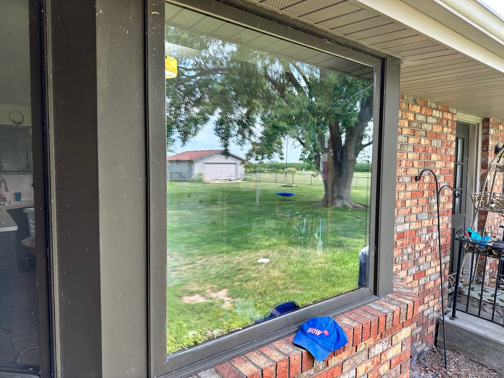 Large residential window installation with brick exterior and backyard view, showcasing WOW window services in Greensboro