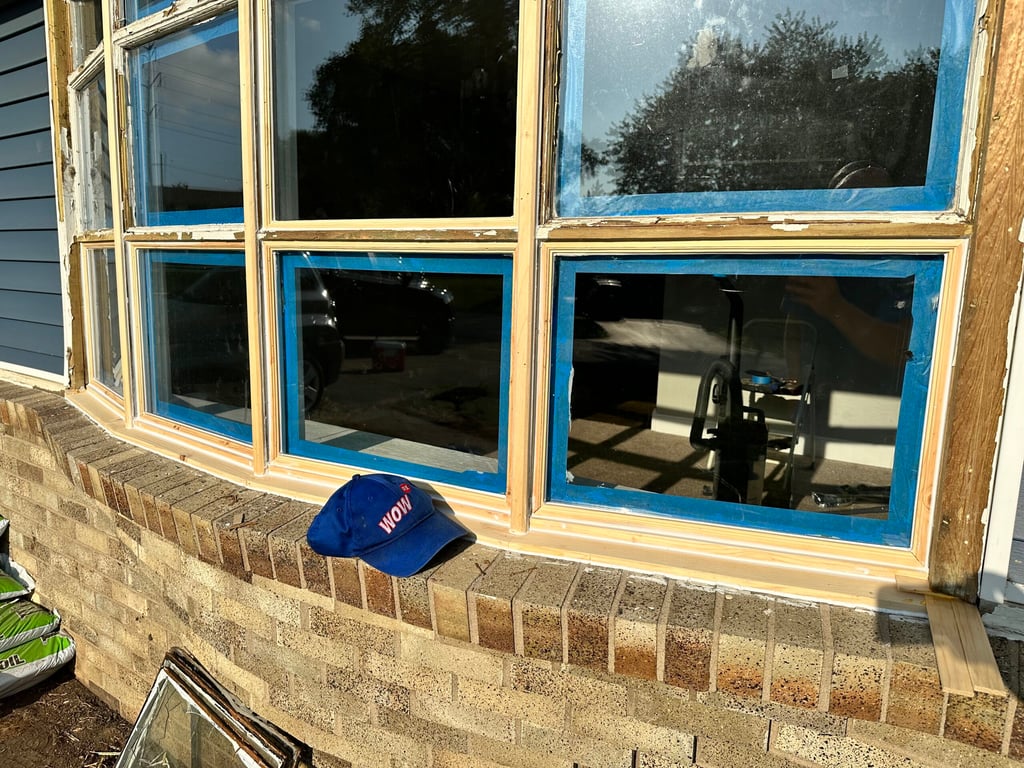 Bay window replacement in progress with blue trim tape and exposed framing on brick foundation in Gastonia, North Carolina