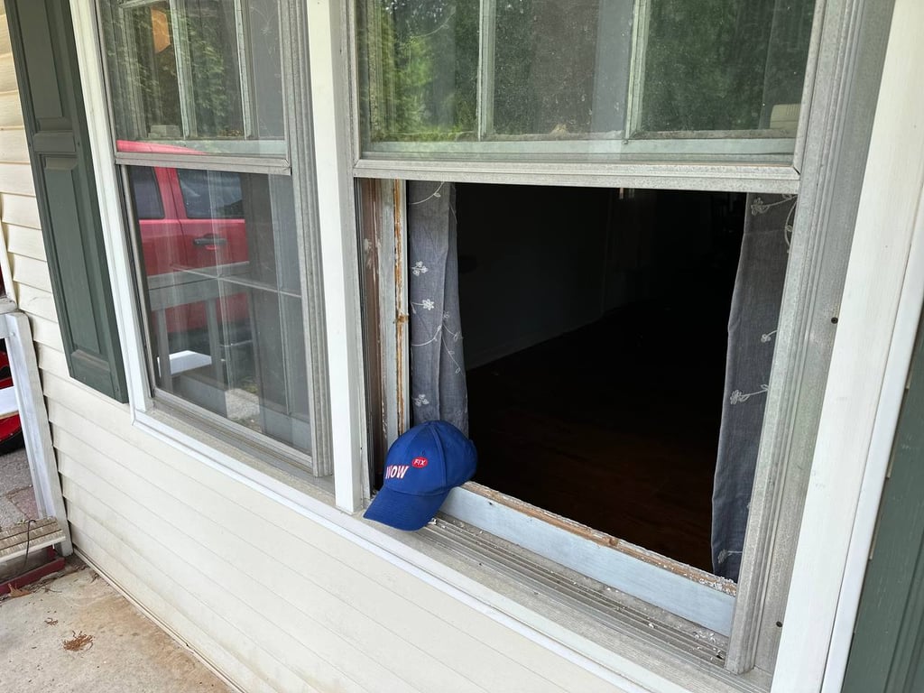 Broken residential window with removed pane showing repair in progress, with WOW service cap visible on window sill