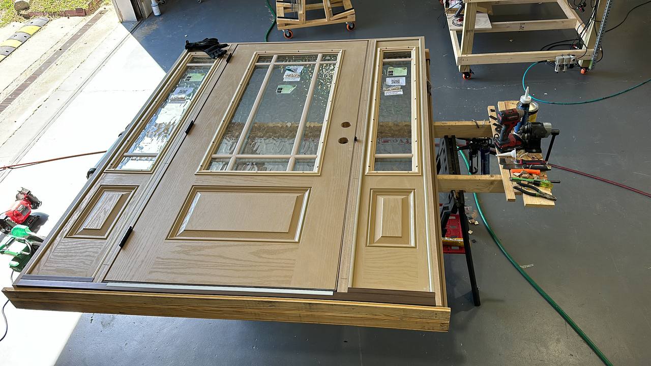 Custom craftsman entry door with decorative glass panels and sidelights being prepared for installation in Charlotte workshop