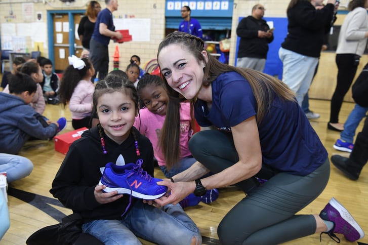 Jenny Simpson giving a pair of New Balance shoes to a Rising New York Road Runners participant at the 1 for You 1 for Youth shoe distribution in Red Hook.