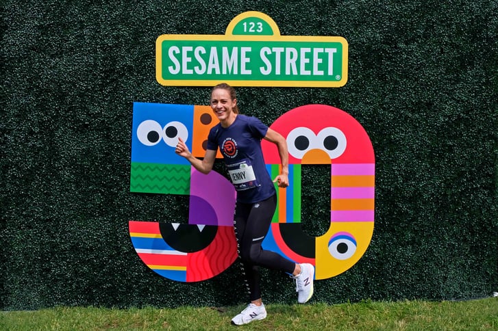 Jenny Simpson in front of the Sesame Street 50th Anniversary logo