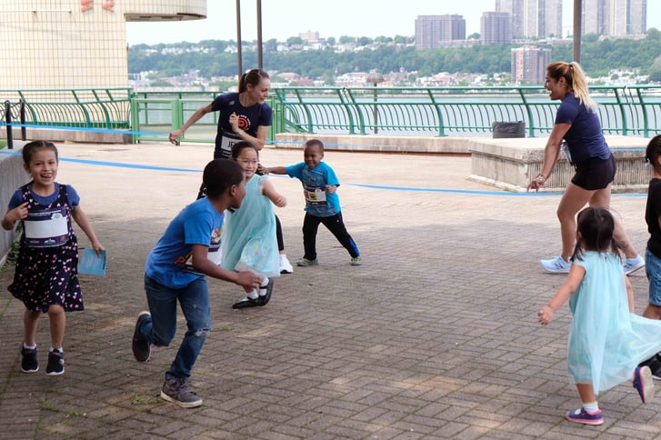 Rising New York Road Runners students playing a game of tag with Jenny Simpson and NYRR staff