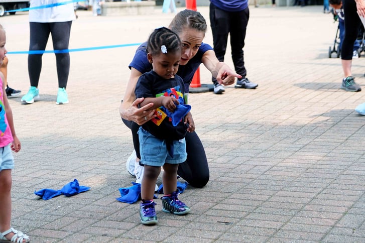 Jenny Simpson guiding a Rising New York Road Runners student at a bean bag toss station