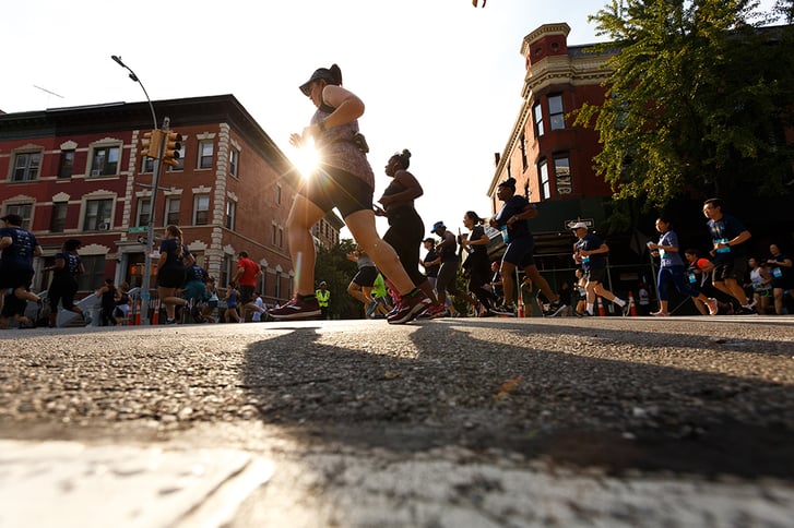 Runners running in front of a sunset on the streets of Harlem