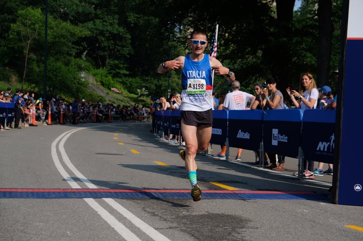 A man finishing the Italy Run, wearing a singlet that says "Italia"