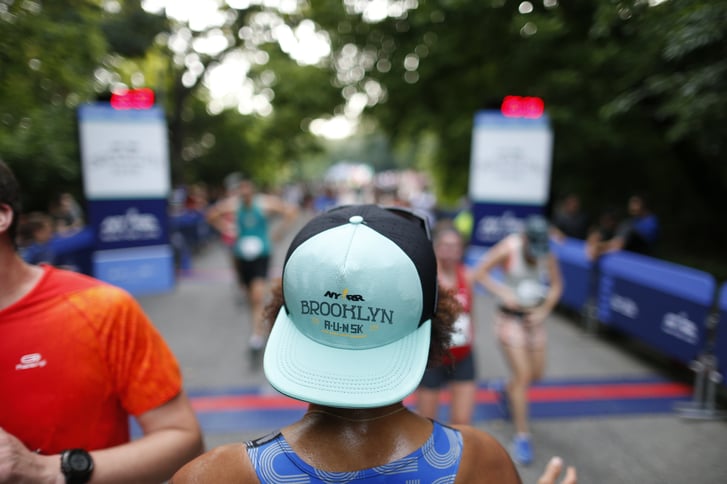 A runner wearing a Brooklyn R-U-N hat at the finish line of the race