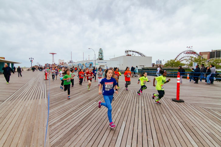 Youth athletes running on the Coney Island Boardwalk at the Brooklyn Half