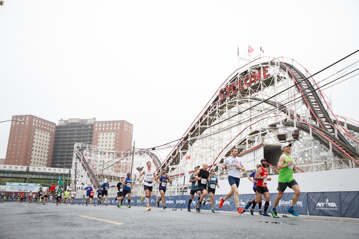 Brooklyn Half runners running next to the Brooklyn Cyclone roller coaster