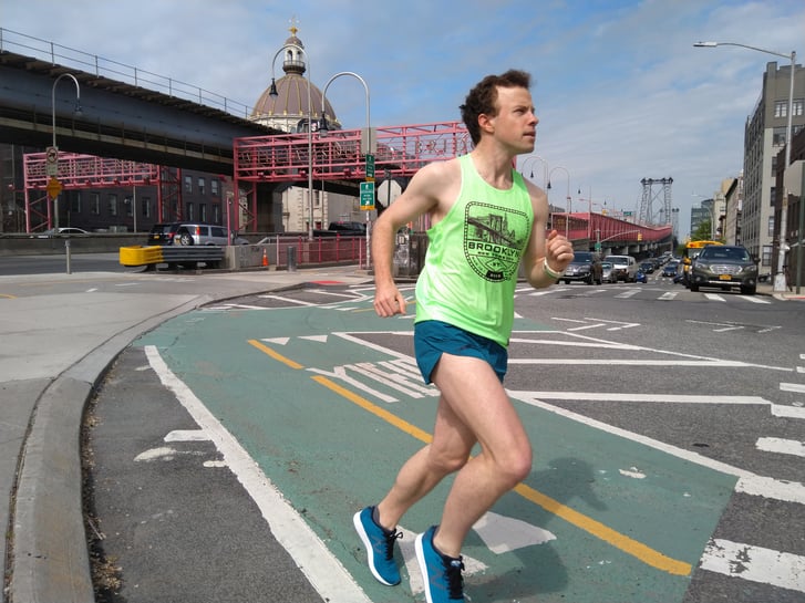 A runner in a bike lane with the Wiliamsburg Bridge in the background