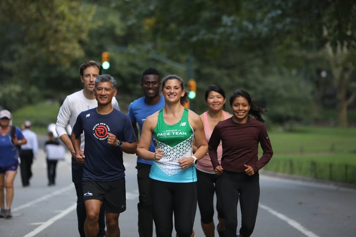 NYRR Coach Melanie Kann wearing the Biofreeze Pace Team singlet surrounded by runners.