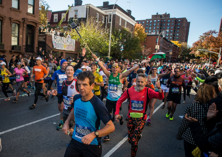 A NYRR Pace Team member running in a crowd on the street