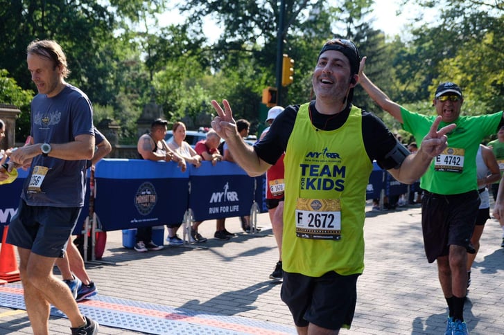 A Team for Kids Runner crossing the Manhattan 7 Mile finish line