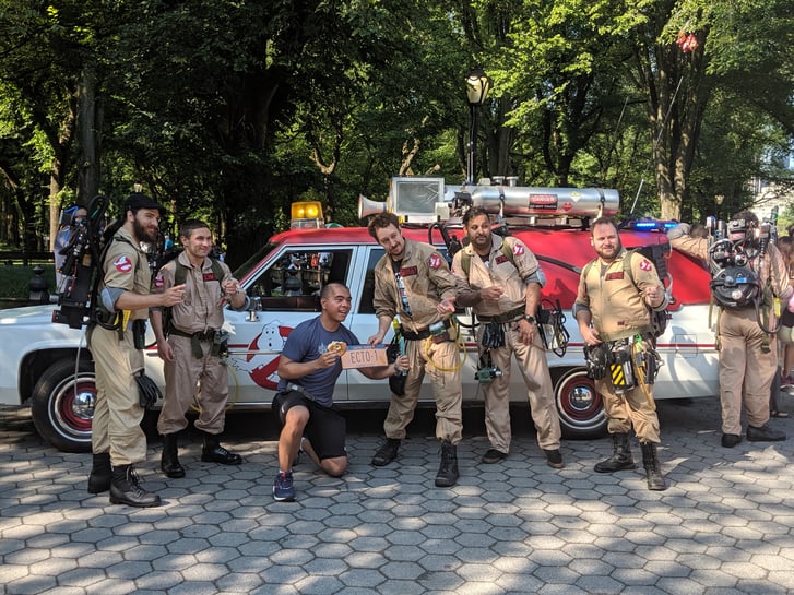 A runner with a team of ghostbusters in front of the Ghostbusters Eco-1 car