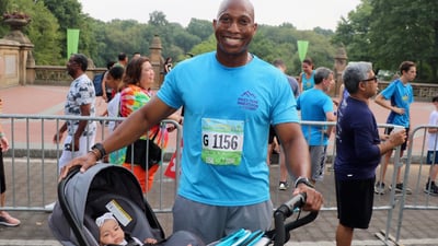 A father after the Summer Community Run with his child in their stroller
