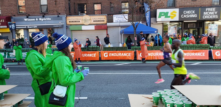 Volunteers with the Exchange Visitor Program hand out water to runners in the TCS NYC Marathon.