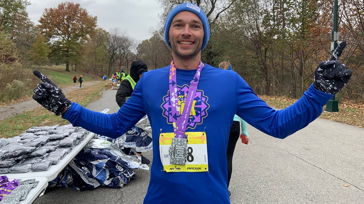 A runner posing with his medal after finishing the NYRR 60K