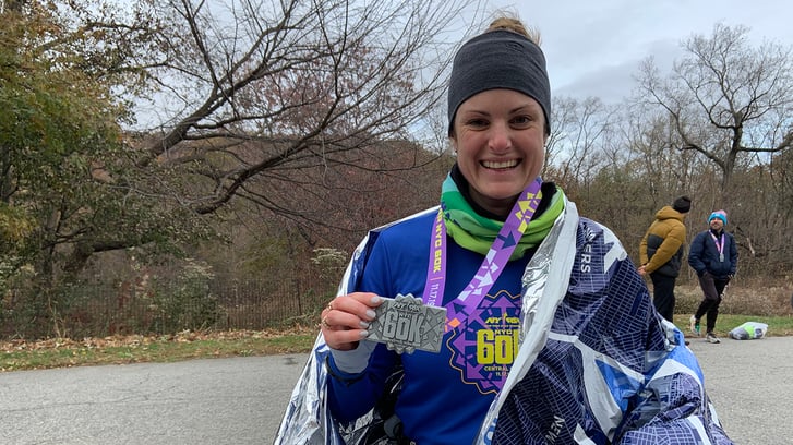 A runner posing with her medal after finishing the NYRR 60K