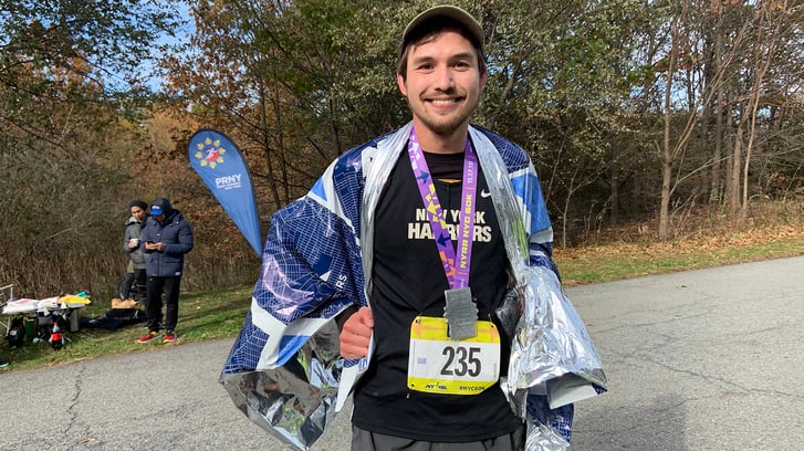 NYRR 60K runner smiling with his medal
