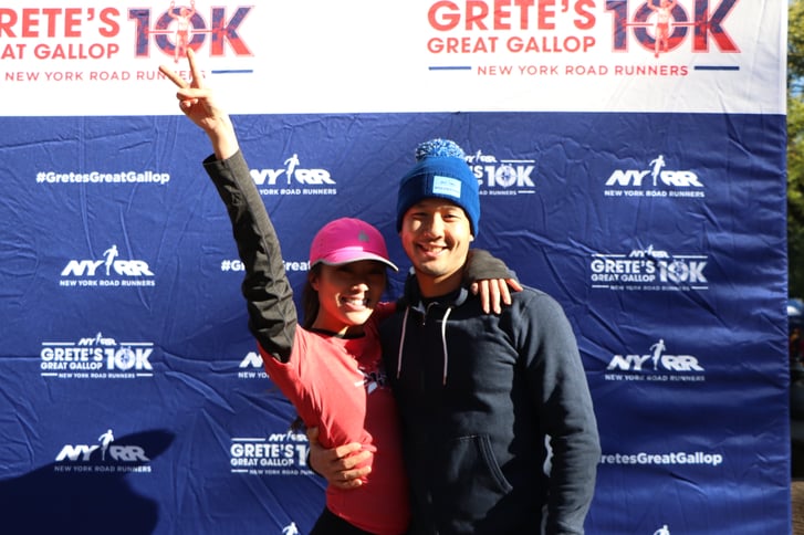 A man and a woman posing in front of the NYRR Grete's Great Gallop 10K Photo Booth