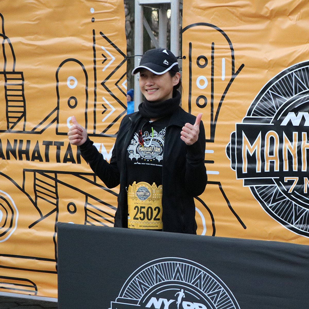 A runner posing in front of the NYRR Manhattan 7 Mile banner