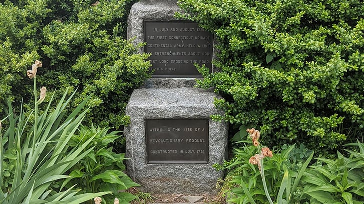 A historical marker reading: "In July and August, 1781 The First Connecticut Brigade, Continental Army, Held a line of entrenchments about 800-feet long across the road at this point. Within is the site of a Revolutionary Redoubt constructed in July 1781.