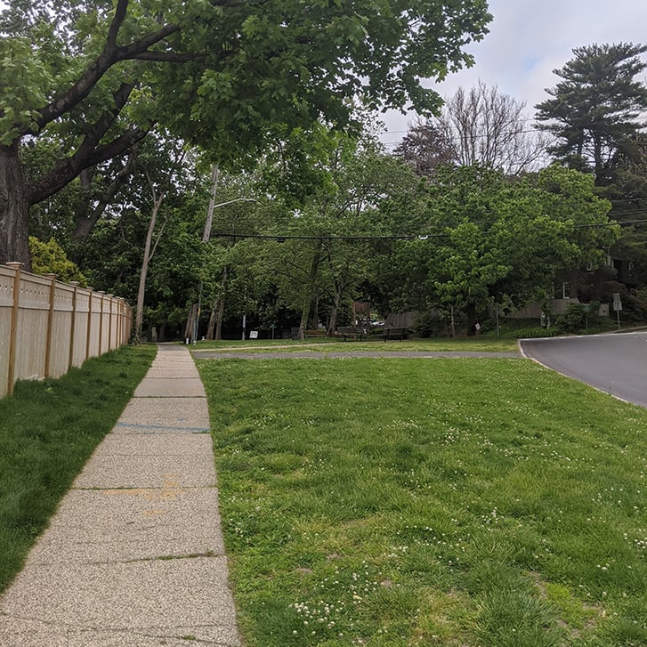A grassy plaza with a sidewalk next to it.