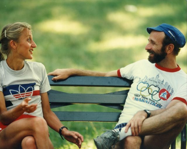 Fred Lebow and Grete Waitz talking on a bench together.
