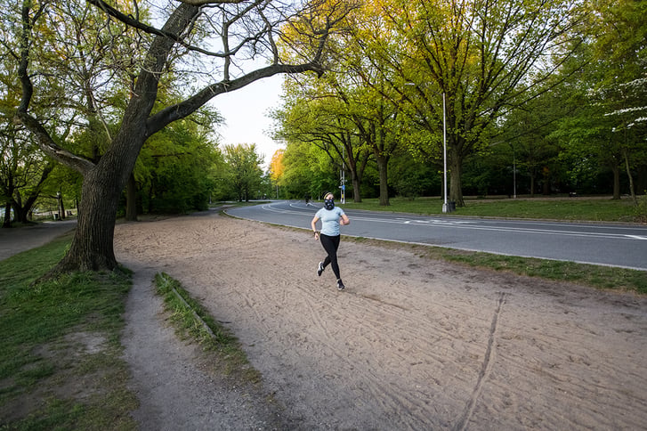 Masked woman runner in Prospect Park landscape