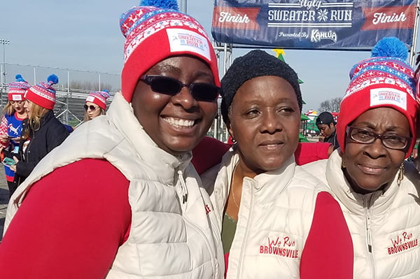 Three members of We Run Brownsville group at a race wearing hats and vests