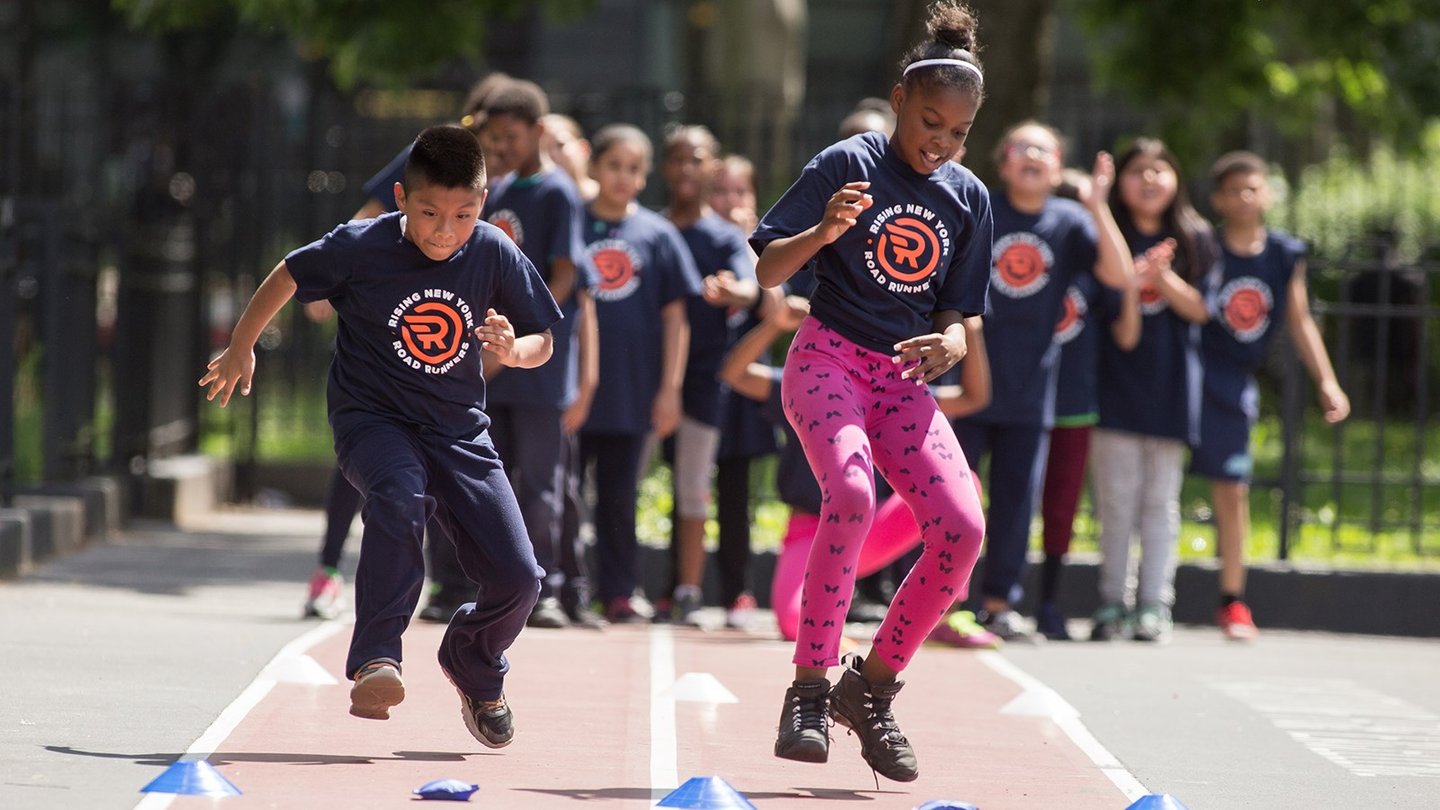 Two Rising New York Road Runners participants on a track doing a running exercise