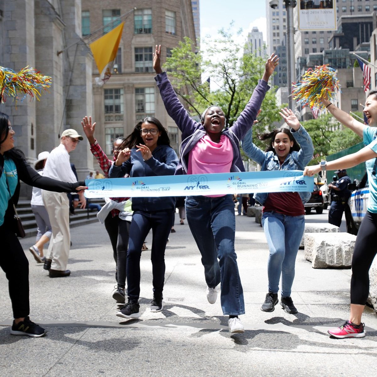 NYRR staff holding up a finish line for runners in a park on Global Running Day
