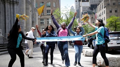 NYRR staff holding up a finish line for runners in a park on Global Running Day
