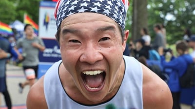 An NYRR staffer wearing a November Project singlet cheering at a race.