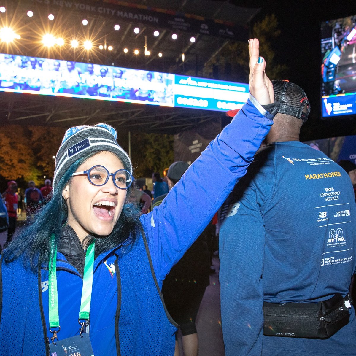 A NYRR staffer high-fiving runners at the finish line of a race.