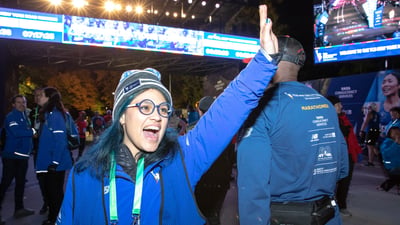 A NYRR staffer high-fiving runners at the finish line of a race.