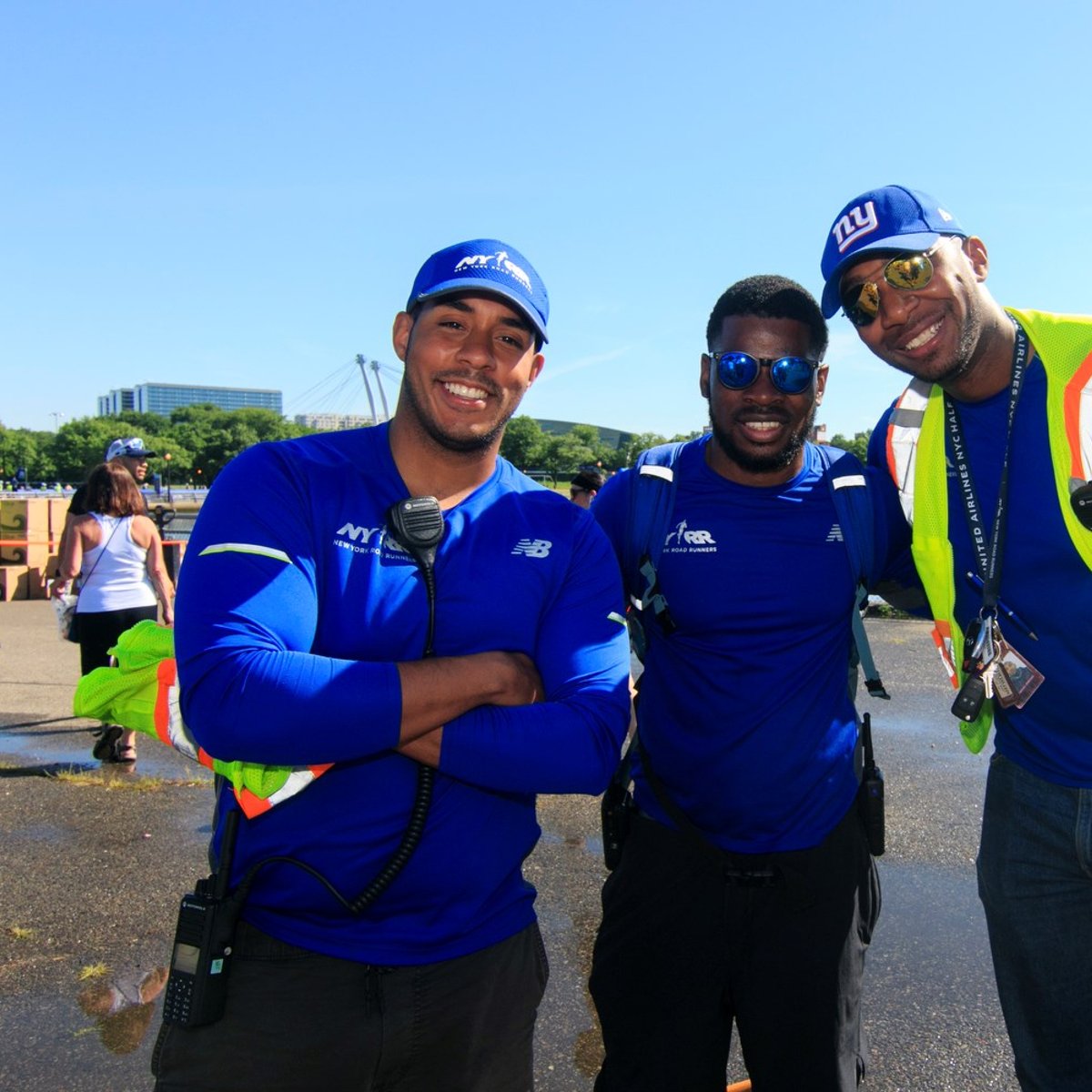Three NYRR staffers at a race, smiling at the camera.