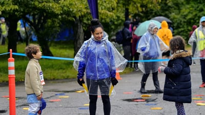 A NYRR staffer talking to two kids at an event.