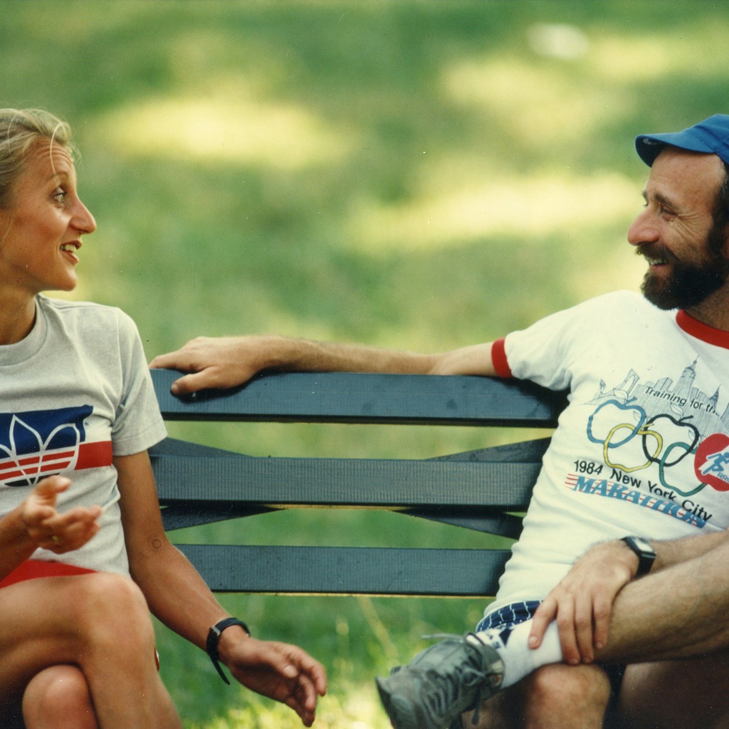 Fred Lebow and Grete Waitz sit on a bench talking in Central Park